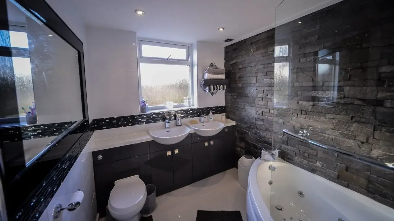 TRJ bathroom interior with dark wall tiles and a bath