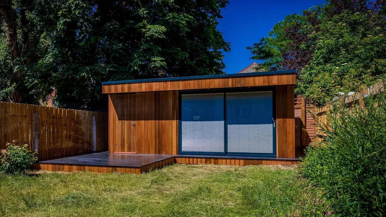 Completed timber-clad TRJ garden room set into a garden