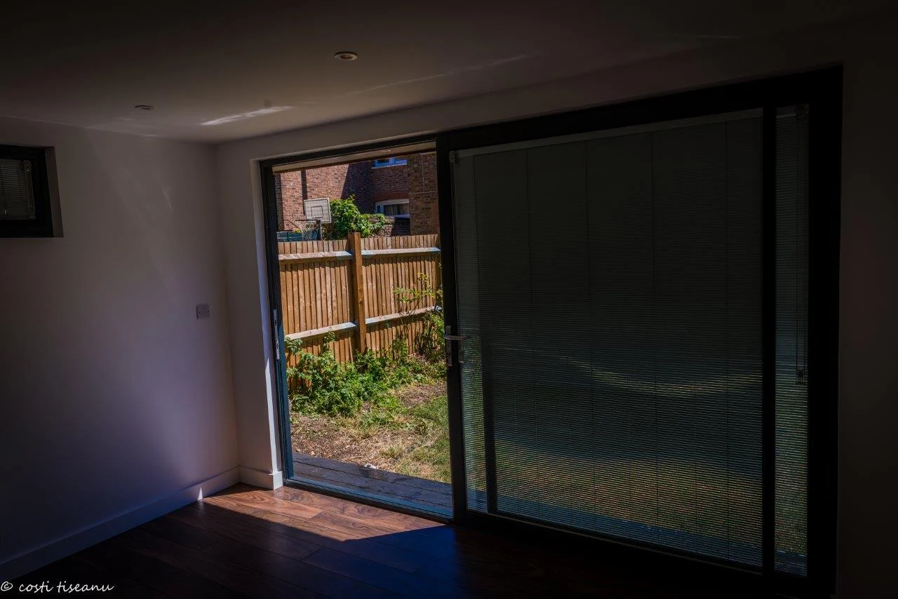 Sliding doors and integral blinds viewed from inside the London garden room