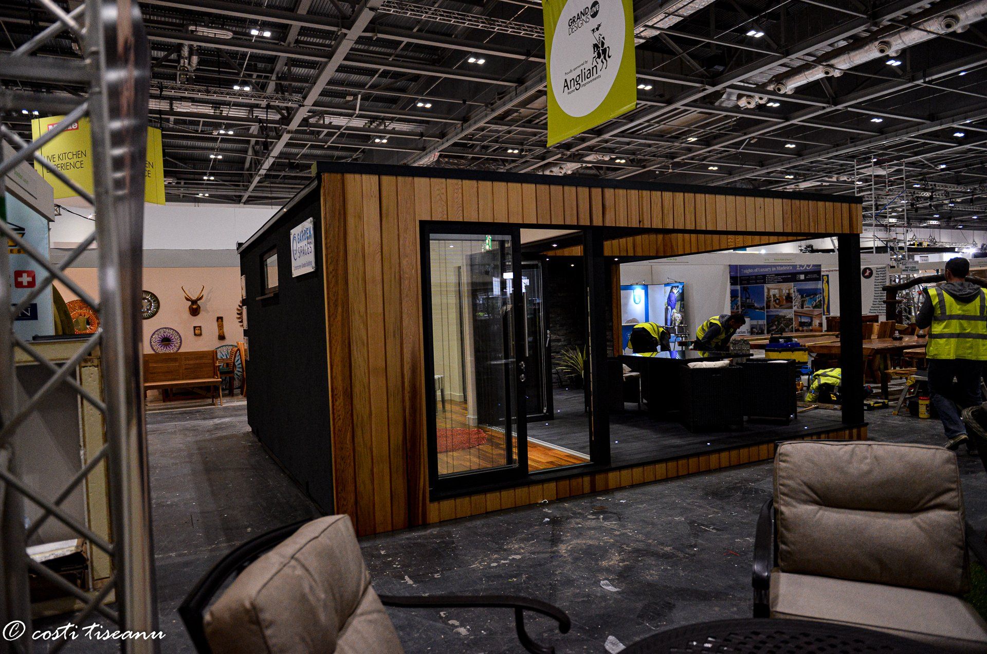 Dark-clad garden-room display beside an exhibition aisle