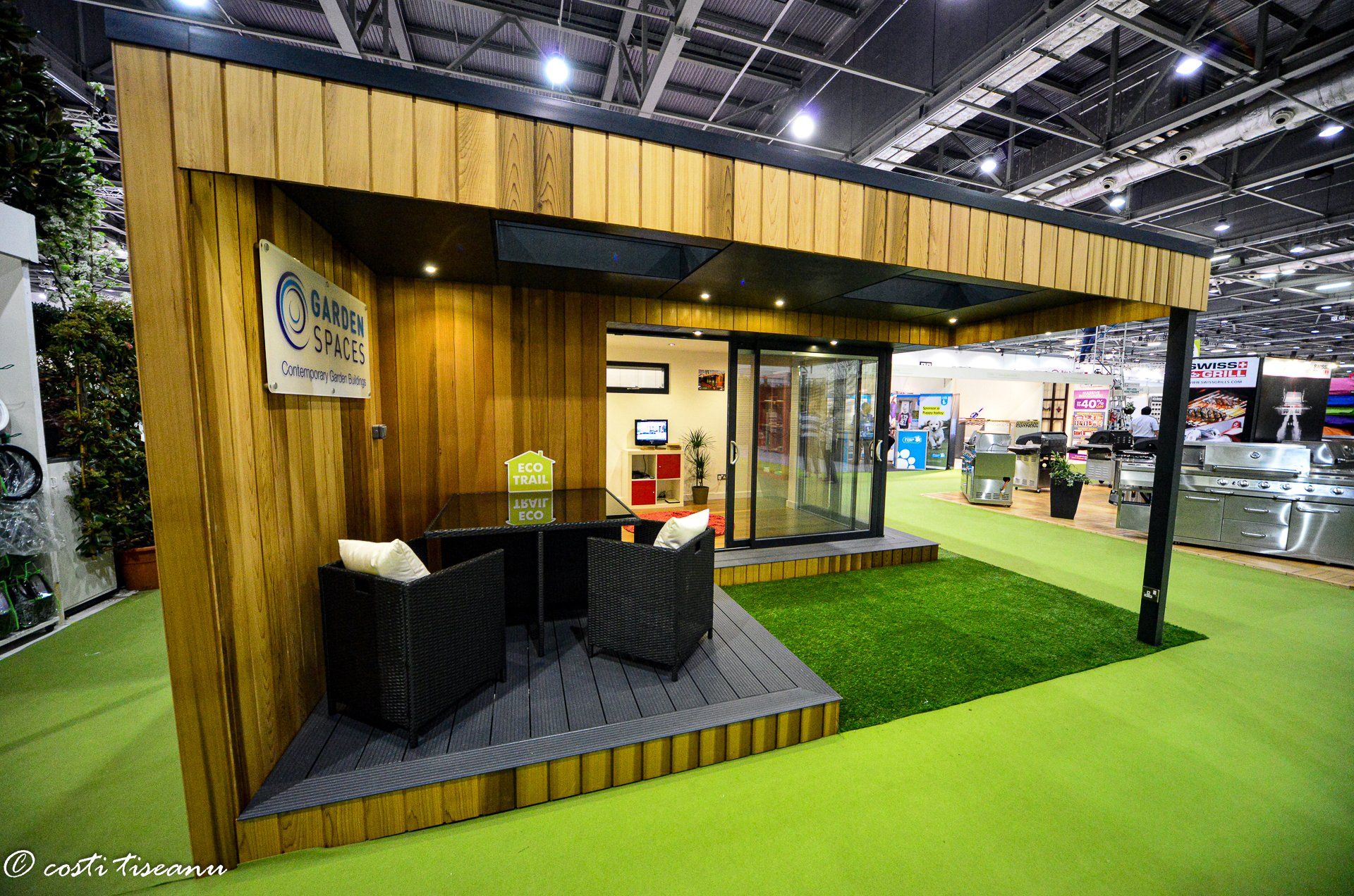 Glazed garden building beside an artificial-grass exhibition area