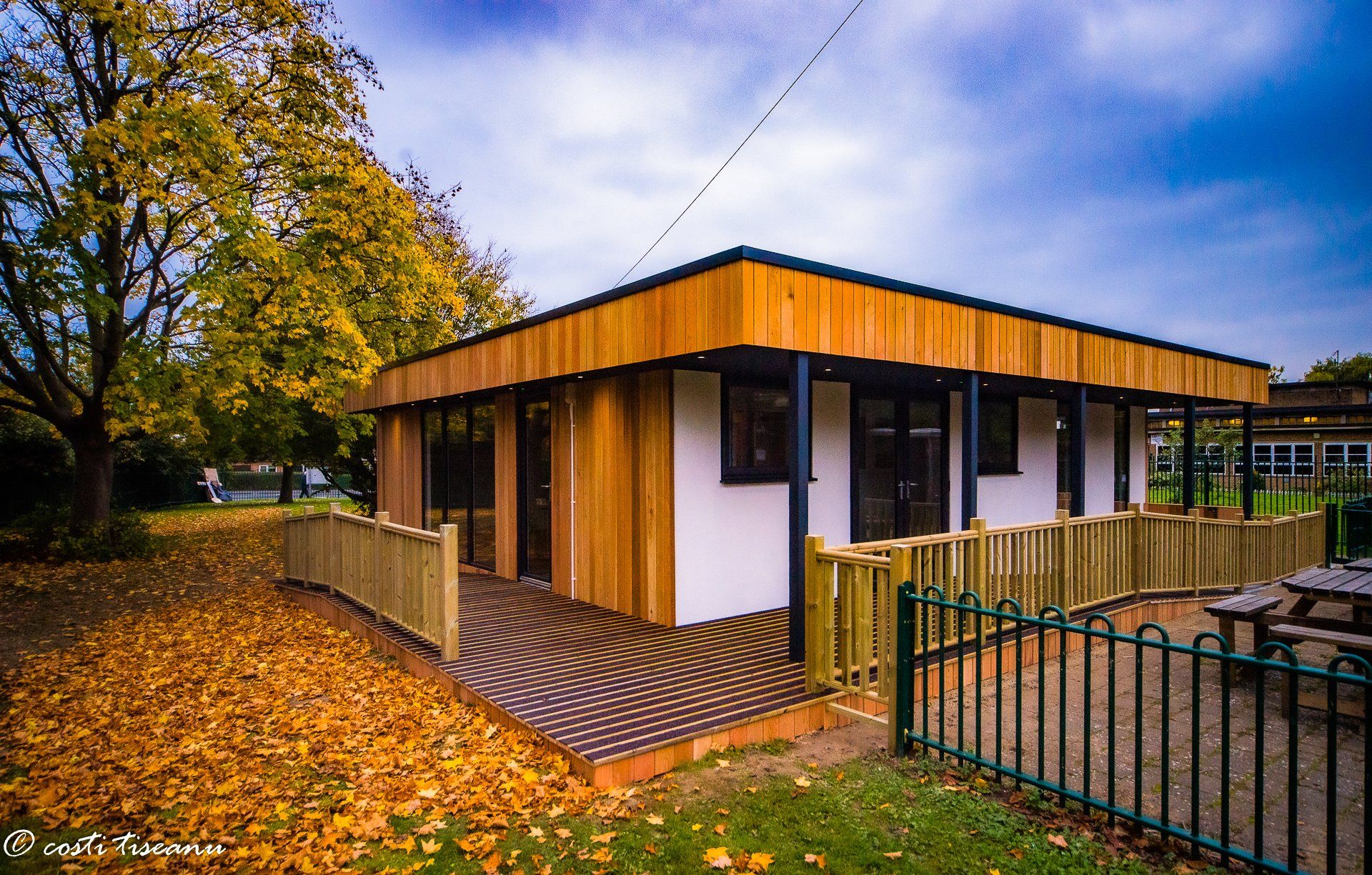 Timber-clad school building with glazing beside an outdoor play area
