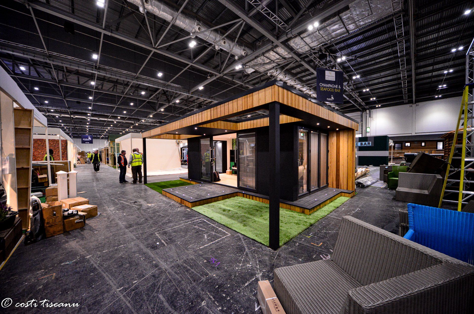 Timber-clad garden building displayed inside an exhibition hall