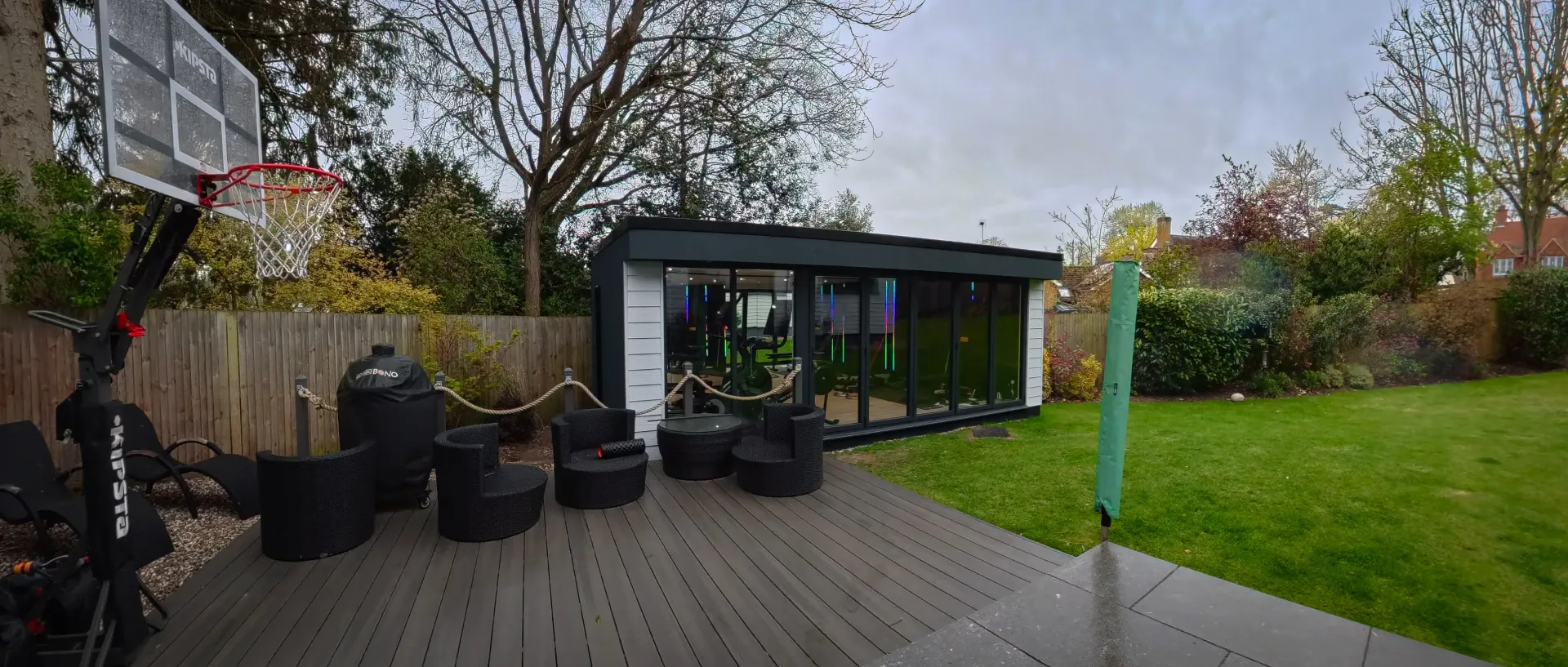 Dark-clad garden room beside a lawn and boundary fence