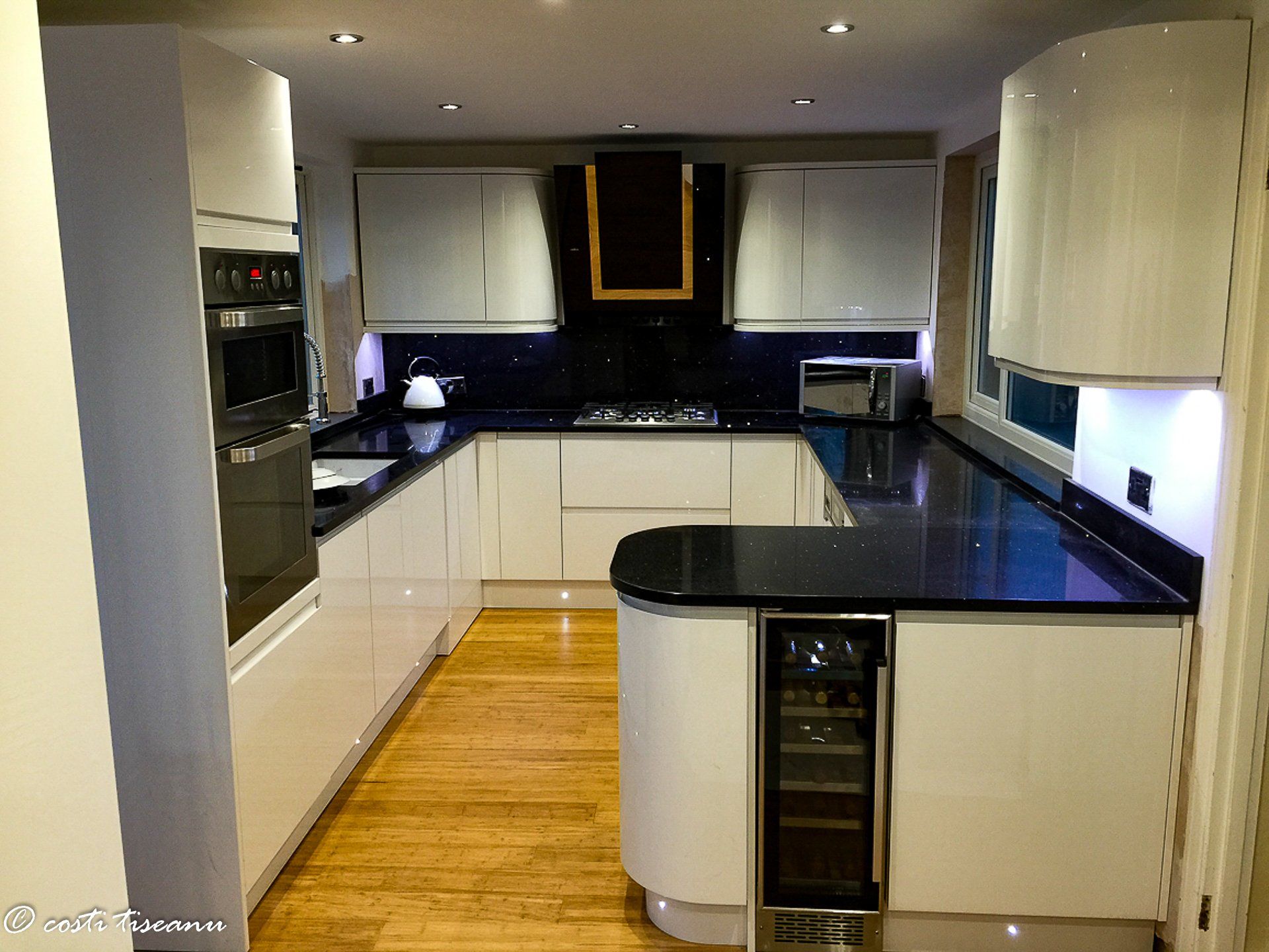 Kitchen with pale cabinetry and dark worktops