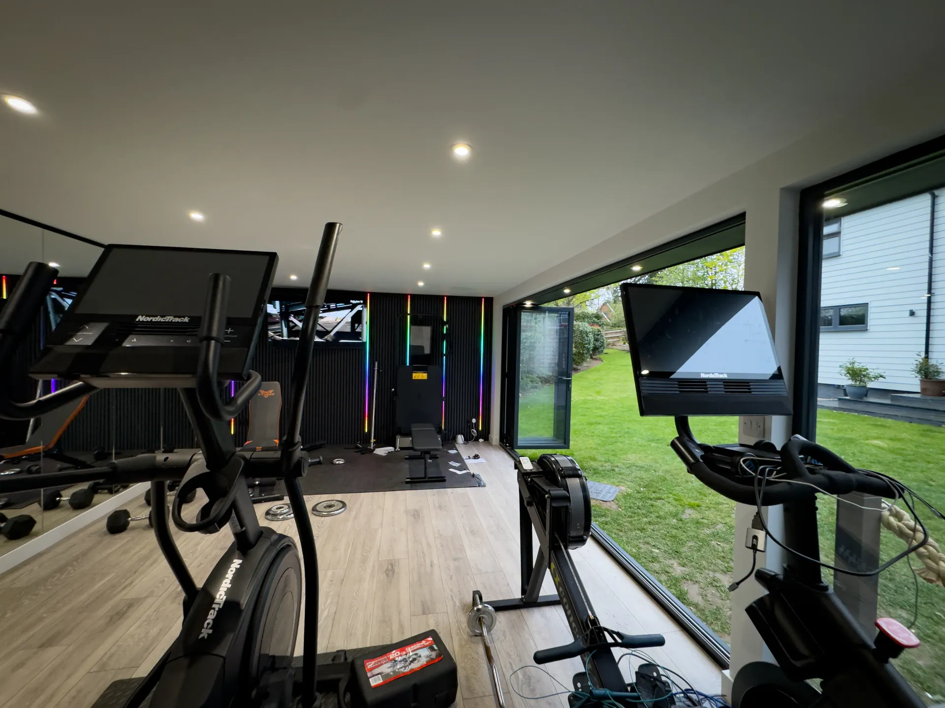 Garden gym interior with cardio machines and glazed garden views